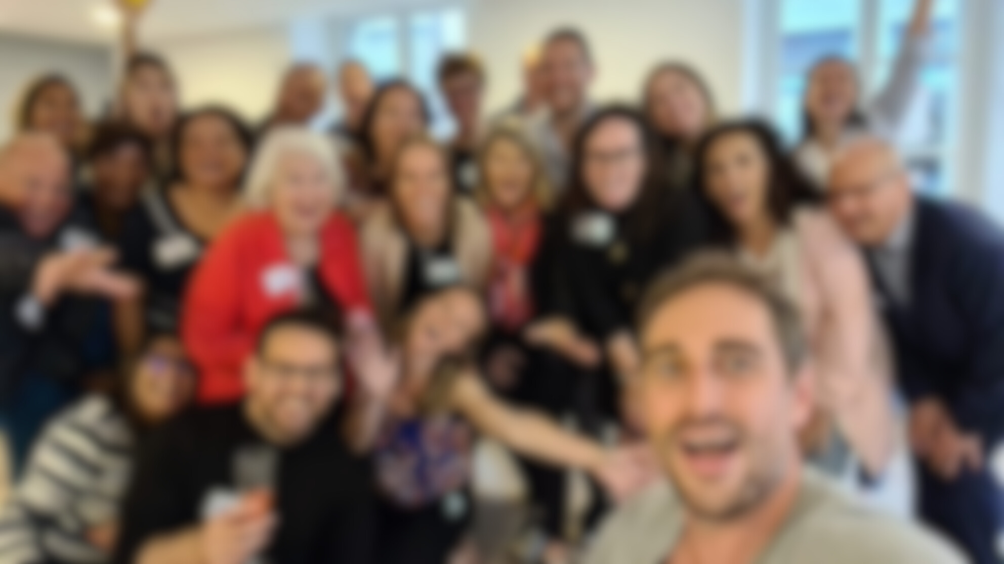Blurred photo of a group of happy people wearing name tags